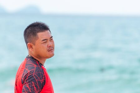 Sanya, China - May 15, 2019: A lifeguard on beach keeps order and safety. T-shirt with the inscription Lifeguard in English and Chinese.のeditorial素材