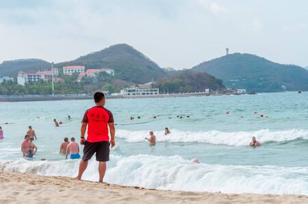 A Chinese lifeguard on Sanya beach keeps order and safety. T-shirt with the inscription Lifeguard in English and Chinese.のeditorial素材