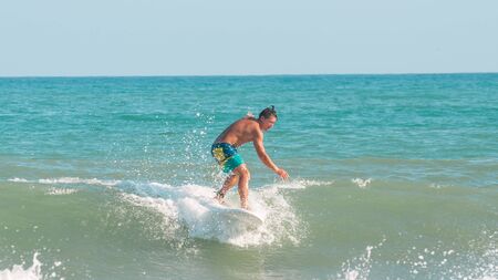 Sanya, hainan, China - May 16, 2019: An unknown young muscular surfer slides beautifully through the azure waves of the South China Sea on a surfboard. Surfing is an extreme beautiful sport.のeditorial素材