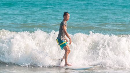 Sanya, hainan, China - May 16, 2019: An unknown young muscular surfer slides beautifully through the azure waves of the South China Sea on a surfboard. Surfing is an extreme beautiful sport.のeditorial素材
