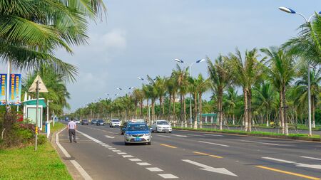 Haikou, Hainan, China - May 12, 2019: Nice view of the roadway. On the dividing line, green tropical palm trees are reinforced with metal structures to protect against frequent typhoons.のeditorial素材