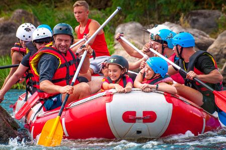 Myhia, Ukraine - August 17, 2019: Rafting. A cheerful group of men and women descends on a large inflatable boat on the river. There is a child in the boat. Sincere emotions of happy people.のeditorial素材