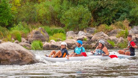 Myhia, Ukraine - August 17, 2019: Rafting. A cheerful friendly family with a child rafting in a rubber inflatable boat on the rapids of a fast river. The concept of a happy family, healthy lifestyle.のeditorial素材
