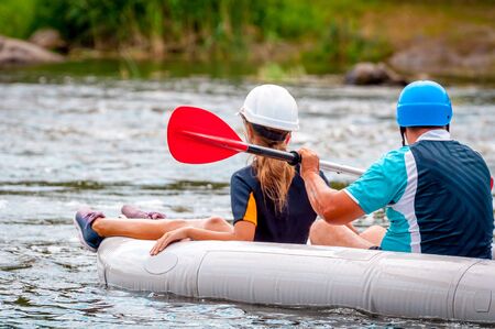 Rafting trip. Father and child rafting on the river in a rubber inflatable boat. The concept of a friendly family, healthy lifestyle.の写真素材