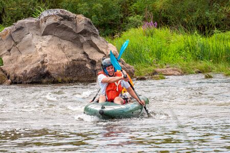 Myhiya, Ukraine - August 17, 2019: Rafting trip. Two rowers are rafting down the river in a rubber inflatable boat. The concept of communication of generations, physical activity of the elderly.のeditorial素材