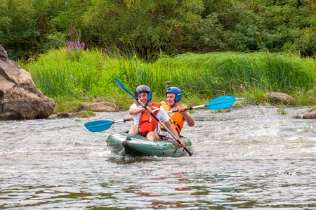 Myhiya, Ukraine - August 17, 2019: Rafting trip. Two rowers are rafting down the river in a rubber inflatable boat. The concept of communication of generations, physical activity of the elderly.のeditorial素材