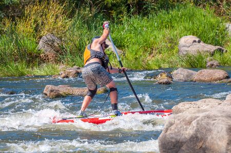 Myhiya, Ukraine - August 17, 2019: Sportsman paddling whitewater river on a inflatable stand up paddle board SUP.のeditorial素材