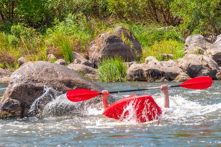 Playboating. A man sitting in a kayak with oars in his hands performs exercises on the water. Kayaking freestyle on whitewater. Eskimo roll.の写真素材