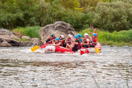 Myhia, Ukraine - August 17, 2019: Rafting. A cheerful group of men and women descends on a large inflatable boat on the river. There is a child in the boat. Sincere emotions of happy people.のeditorial素材