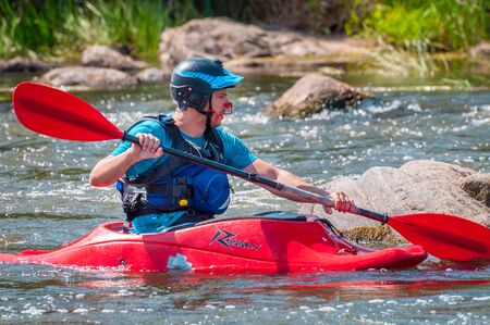 Myhiya, Ukraine - August 17, 2019: Playboating. A man sitting in a kayak with oars in his hands performs exercises on the water. Kayaking freestyle on whitewater.のeditorial素材
