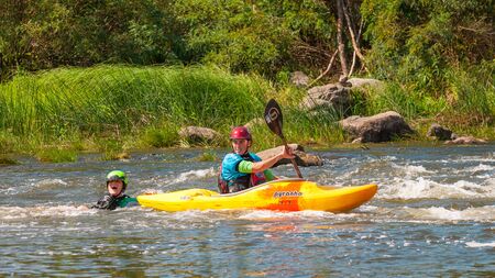 Myhiya, Ukraine - August 17, 2019: Playboating. Kayaking freestyle on whitewater. During training, the girl fell from her kayak into the water, a friend saves her. The situation is under control.のeditorial素材