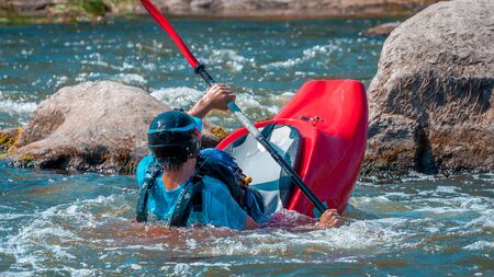 Playboating. A man sitting in a kayak with oars in his hands performs exercises on the water. Kayaking freestyle on whitewater. Eskimo roll.の写真素材