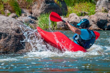 Playboating. A man sitting in a kayak with oars in his hands performs exercises on the water. Kayaking freestyle on whitewater. Eskimo roll.の写真素材