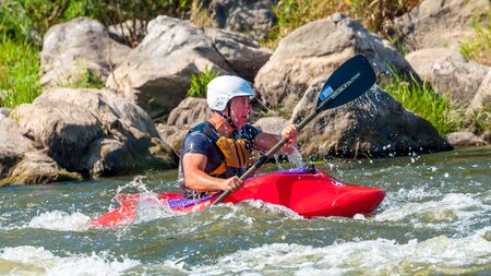 Myhiya, Ukraine - August 17, 2019: Playboating. A man sitting in a kayak with oars in his hands performs exercises on the water. Kayaking freestyle on whitewater.のeditorial素材