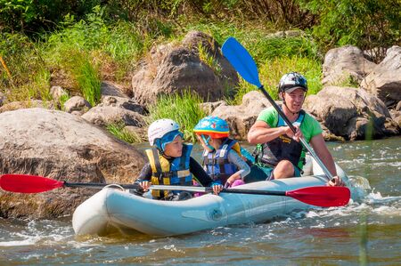 Myhiya, Ukraine - August 17, 2019: Rafting. Father with two children descend on an inflatable boat on the river. Sincere emotions of people. Happy family concept.のeditorial素材