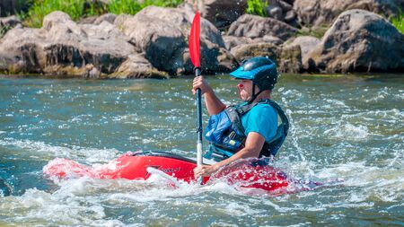 Myhiya, Ukraine - August 17, 2019: Playboating. A man sitting in a kayak with oars in his hands performs exercises on the water. Kayaking freestyle on whitewater.のeditorial素材