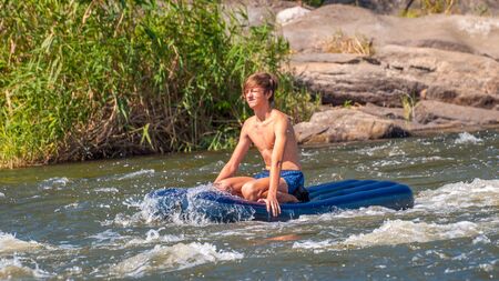 Myhiya, Ukraine - August 17, 2019: Rafting. A young guy descends on an air mattress along a fast riverのeditorial素材