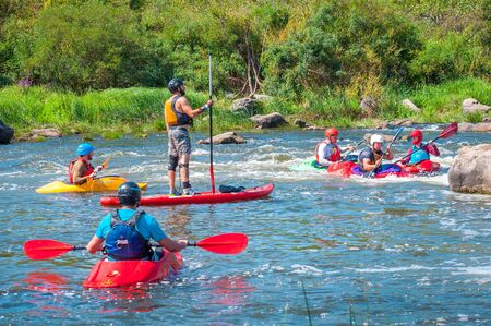 Myhiya, Ukraine - August 17, 2019: Athletes kayakers during training on whitewater and man on inflatable stand up paddle board SUP.のeditorial素材