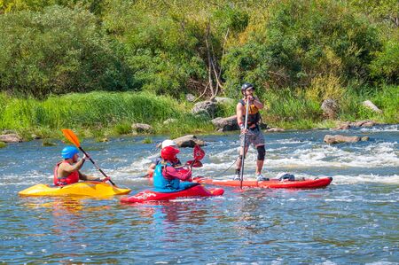 Myhiya, Ukraine - August 17, 2019: Athletes kayakers during training on whitewater and man on inflatable stand up paddle board SUP.のeditorial素材