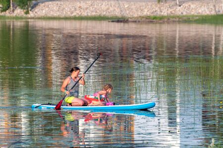 Finland - August 1, 2018. Ukkohalla Ski Resort is located in Central Finland. In summer, water sports and recreation are practiced on the lake. Mom with a child in a rubber boatのeditorial素材