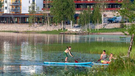 Finland - August 1, 2018. Ukkohalla Ski Resort is located in Central Finland. In summer, water sports and recreation are practiced on the lake. Mom with a child in a rubber boatのeditorial素材