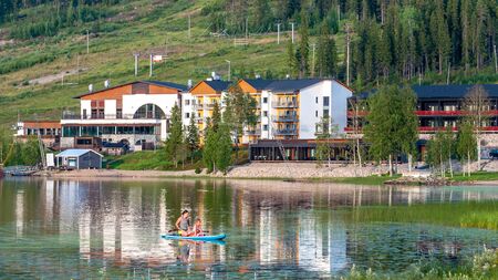Finland - August 1, 2018. Ukkohalla Ski Resort is located in Central Finland. In summer, water sports and recreation are practiced on the lake. Mom with a child in a rubber boatのeditorial素材