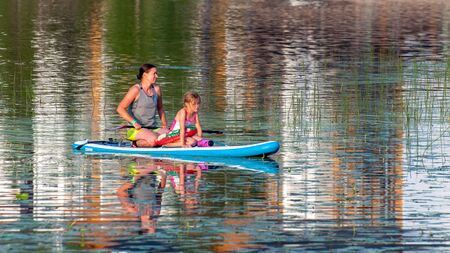 Finland - August 1, 2018. Ukkohalla Ski Resort is located in Central Finland. In summer, water sports and recreation are practiced on the lake. Mom with a child in a rubber boatのeditorial素材