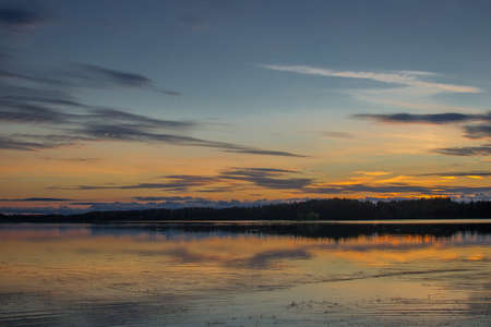 Beautiful sunset landscape over a Finnish lake. The space is flooded with goldの写真素材