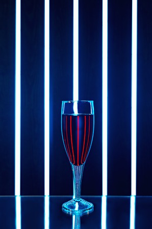 Glass of red wine on a dark background with reflection and streaks of bright light