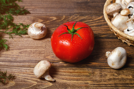 big wet fresh tomato, mushrooms, champignons on old wooden table with greens and dillの写真素材