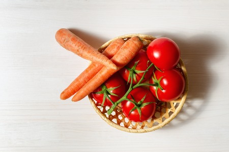 tomatoes and carrots on white wooden tableの写真素材