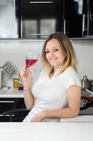 successful beautiful girl drinking red wine in the kitchenの写真素材