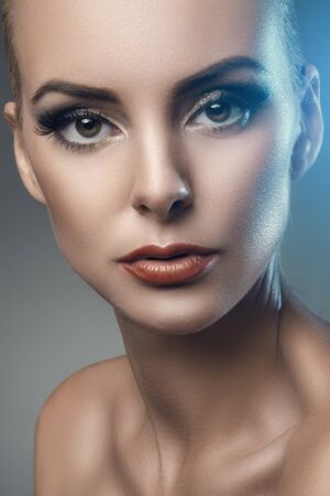 fashion studio portrait of young beautiful woman on dark background, blue backlightの写真素材