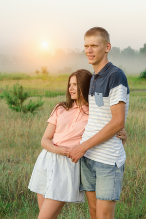 Young romantic loving couple stands in the middle of the field at sunriseの写真素材