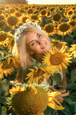 young beautiful woman on blooming sunflower field in summerの写真素材