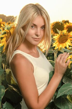 young beautiful woman on a flowering field of sunflowersの写真素材