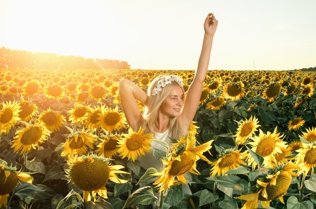young beautiful woman on blooming sunflower field in summerの写真素材