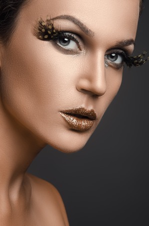 Portrait of beautiful woman in studio with big false eyelashes on a dark backgroundの写真素材
