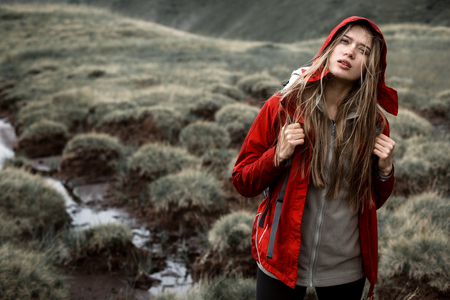 Shot of a young woman looking at the landscape while hiking in the mountains.Outdoor shot of attractive young woman with backpack standing in a mountain stream. Female hiker in creek water.の写真素材