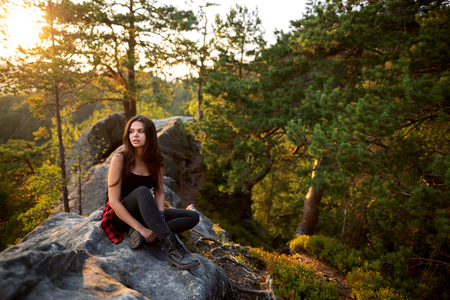 Young tourist with backpack relaxing on rock and enjoying sunsetの写真素材