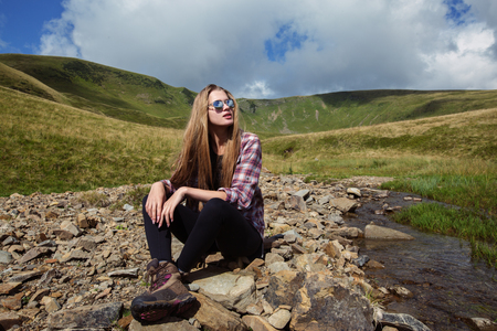 attractive young woman sitting by a mountain streamの写真素材