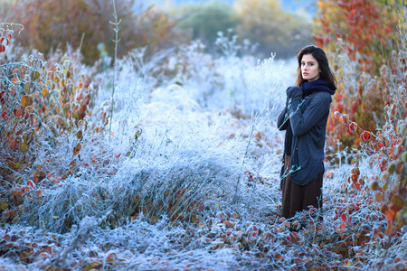 Beautiful sunrise with frost. Portrait of a beautiful girl freezing in the winter forest. Woman in...