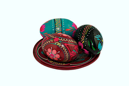 Three painted handmade wooden easter eggs on a wooden plate isolated on a white background  の写真素材