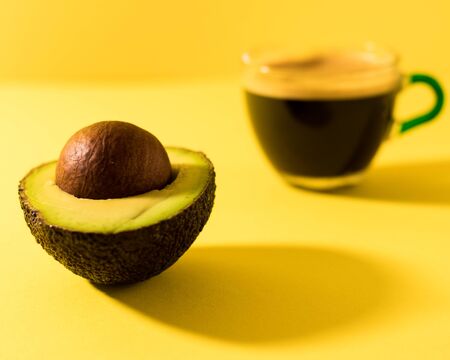Fresh ripe avocado with coffee on yellow background. Avocado with seed.の写真素材