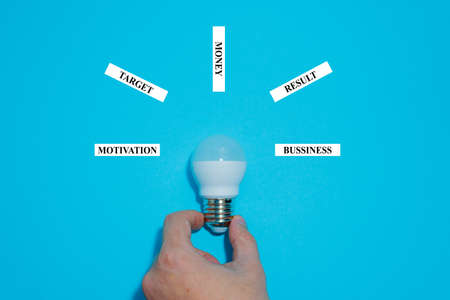 Caucasian's hand hold white eco lamp bulb isolated on blue background. Business concept. Copy space placeの写真素材