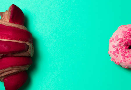 Pink dough and red croissant on green background with place for text in center.の写真素材