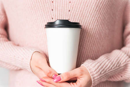 Girl holding white paper cup of takeaway coffee in the hand. Place for your text or log. Winter and Christmas time concept.の写真素材