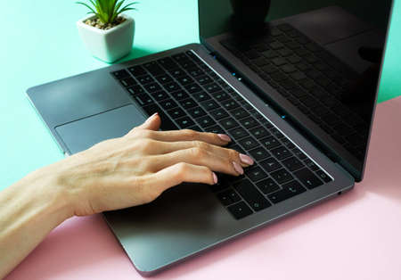 Female hand working on modern laptop. Young girl typing on keyboard at indoor workplace. Close up photo. Business, education concept.の写真素材