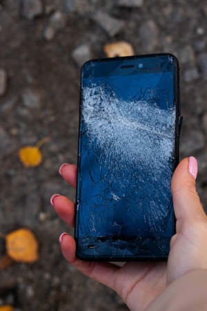 Woman hold broken black phone. Female hand hold broken smart phone. Phone broken touch screen