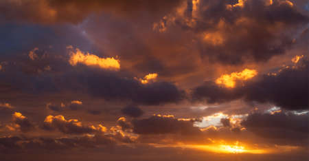 Sunbeams breaking through the dark clouds at sunset. Only sky, no land.